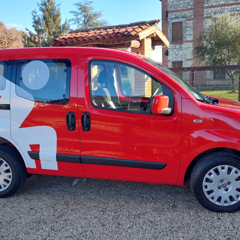 Auto sostitutiva rossa con grafica bianca, parcheggiata all'aperto.