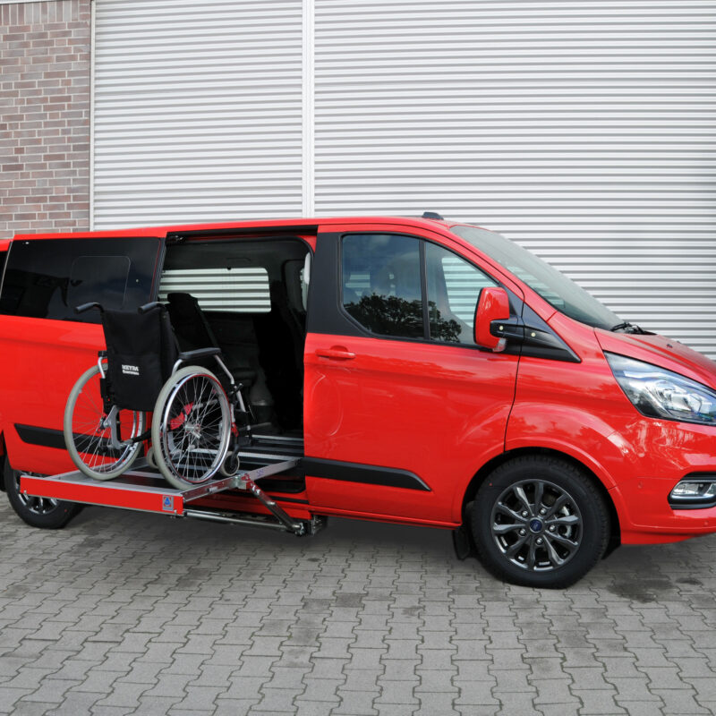 Sollevatore K70: furgone rosso con pedana per sedia a rotelle abbassata