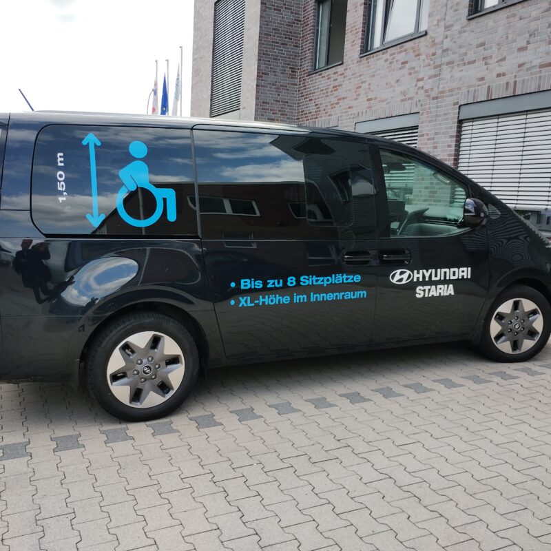 Hyundai Staria A: Minivan nero con simbolo accessibilità e testo in tedesco